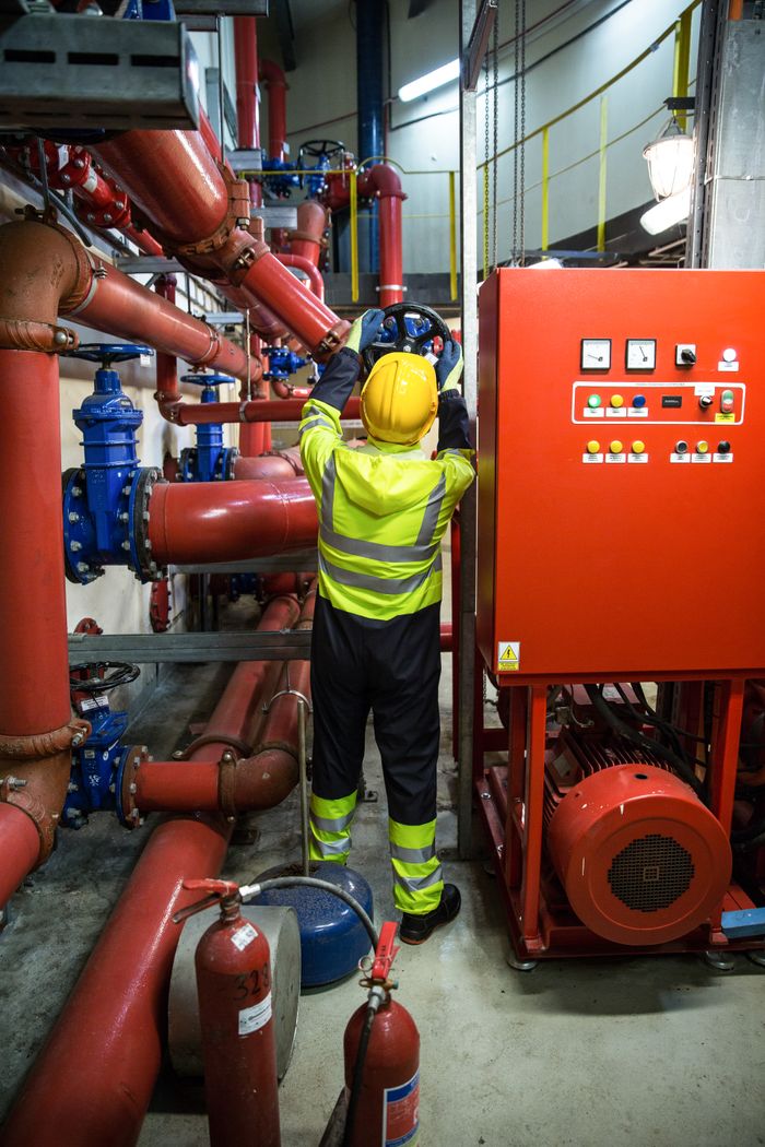 NAVANDA – GIẢI PHÁP CƠ ĐIỆN (M&E) & XỬ LÝ NƯỚC TOÀN DIỆN Worker in uniform operates machinery in industrial setting, emphasizing safety and productivity.