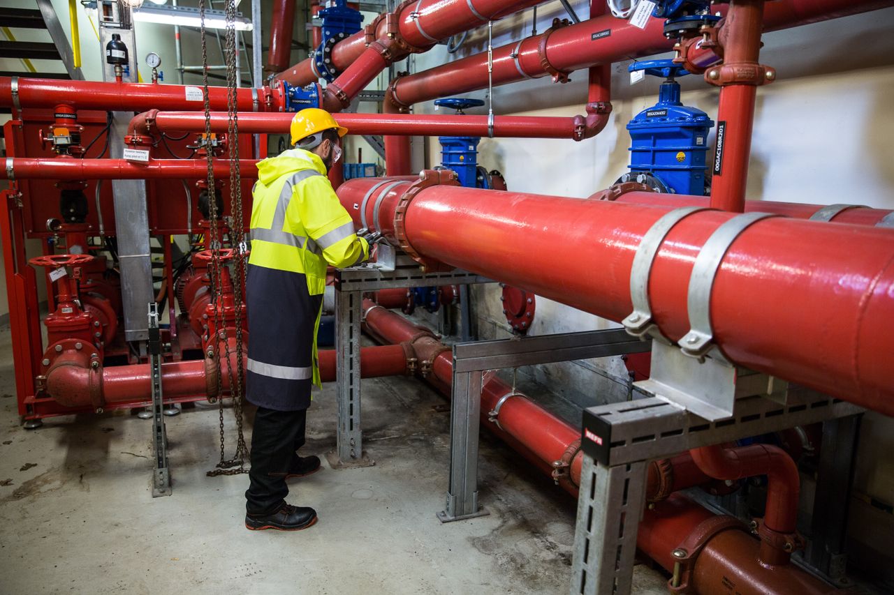 why-choose-us Engineer with safety gear inspecting red industrial piping system indoors.