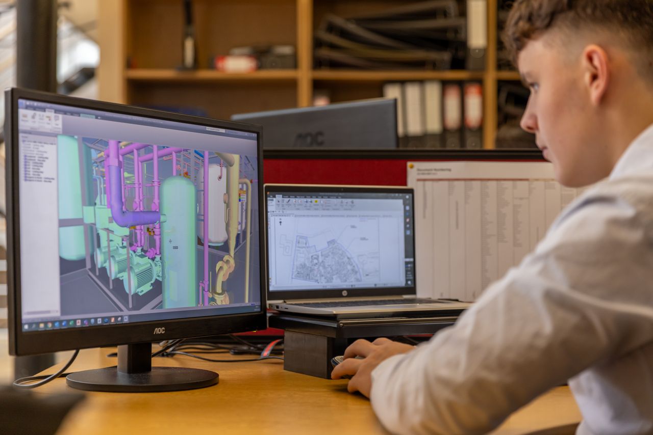 services-03 Engineer working with CAD software on dual monitors in an office setting.