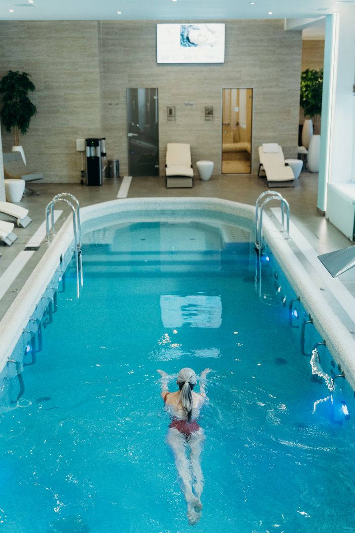 gallery-5 Woman swimming in a luxury indoor spa pool, perfect for relaxation and wellness.